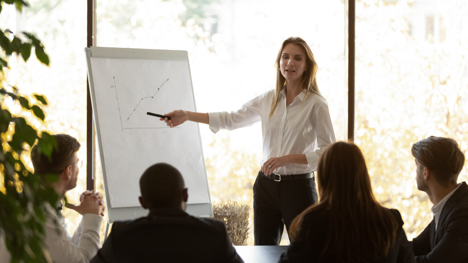 Femme donne une présentation sur un tableau de conférence lors d'une réunion de formation